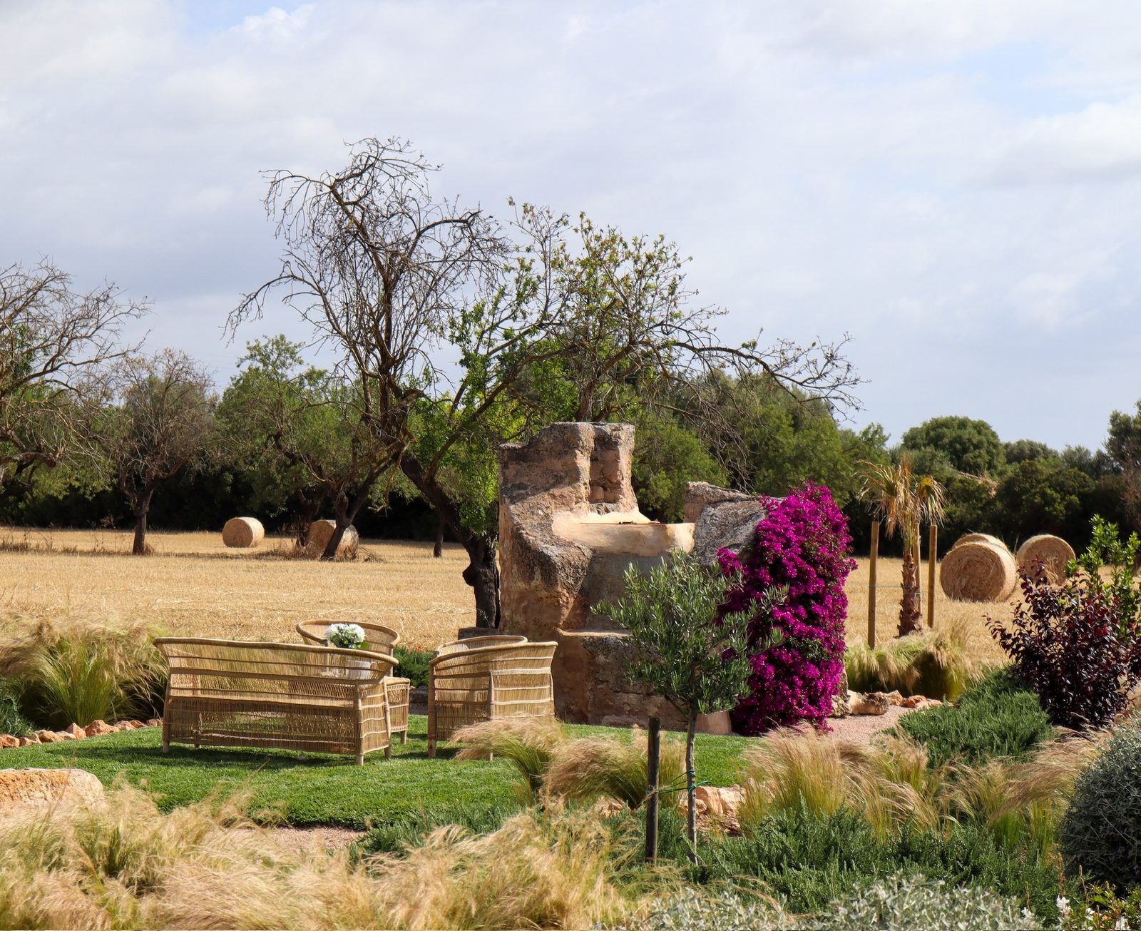 Country garden with hay bales, bougainvillea and woven outdoor furniture